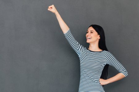 Frau lächelt und steht in Superhelden Pose